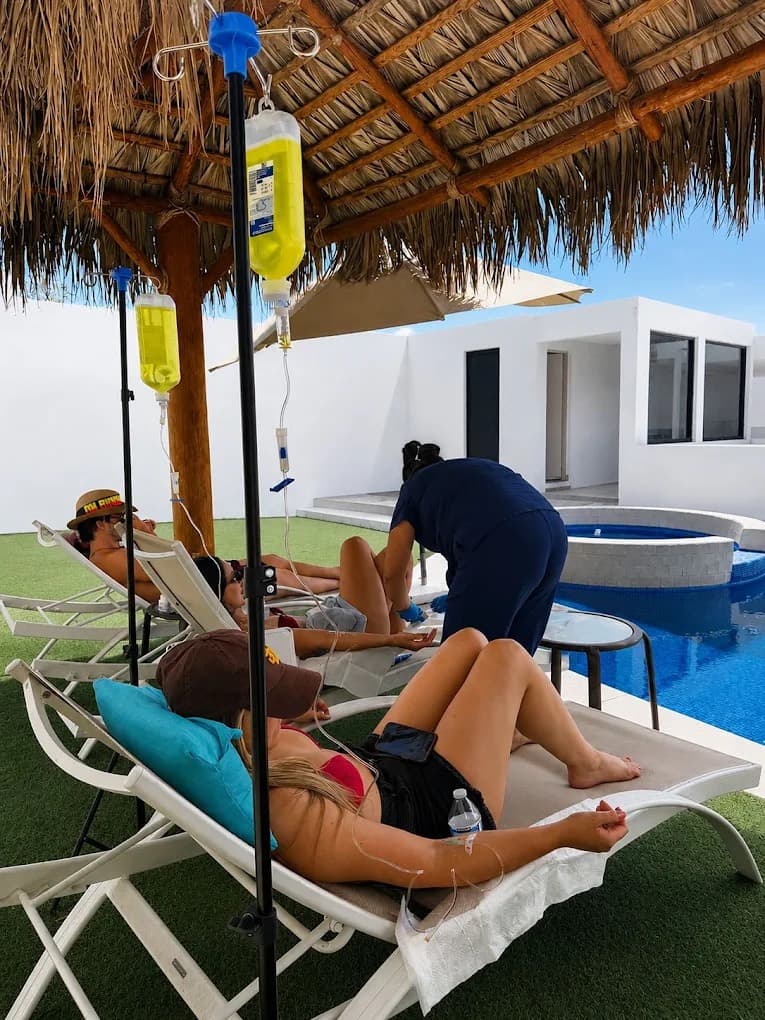 Nurse attending guests receiving IV hydration by the pool at a Los Cabos villa